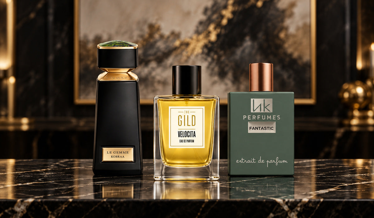 Bvlgari Le Gemme Kobraa, THE GILD Velocita and hkPERFUMES Fantastic on a dark marble retail counter with blurred ivory and bronze artwork.