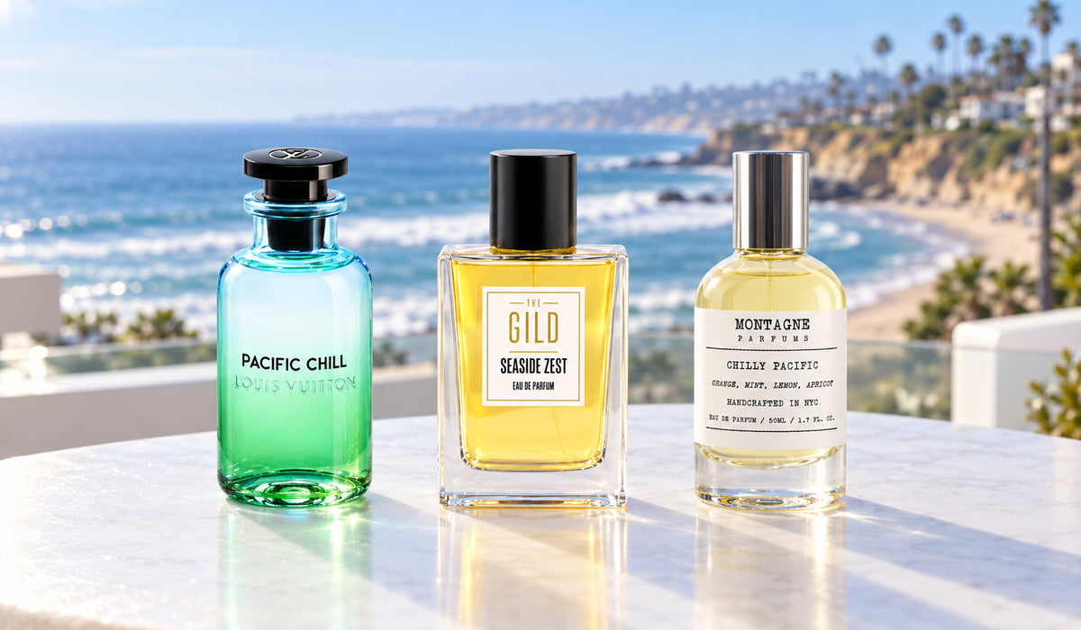 Louis Vuitton Pacific Chill, THE GILD Seaside Zest and Montagne Chilly Pacific on a white outdoor table with a blurred San Diego beach and coastline behind.