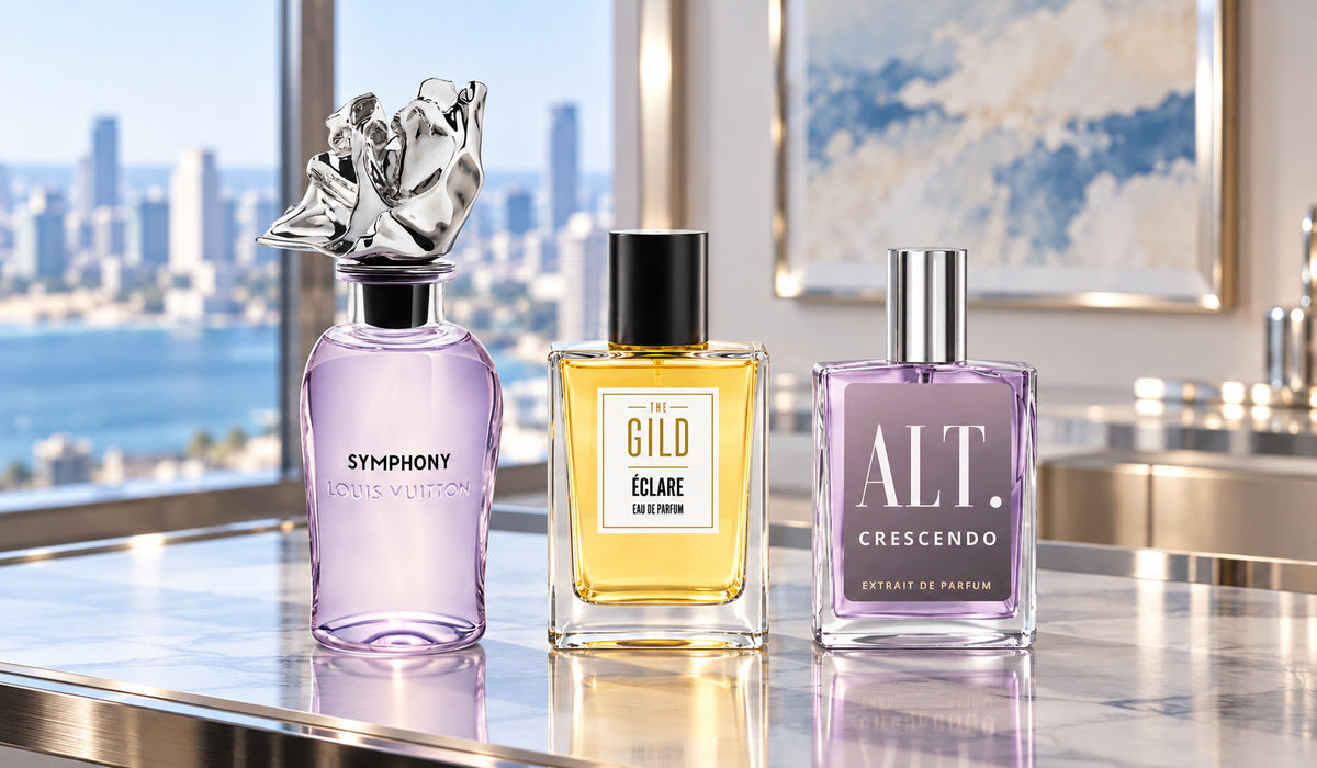 Louis Vuitton Symphony, THE GILD Éclare and ALT Crescendo on a silver display near a window with a softly blurred coastal city and blue and cream artwork.