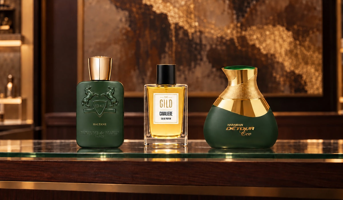 Parfums de Marly Haltane, THE GILD Cavaliere and Al Haramain Detour Eco on a luxury retail shelf with a blurred brown and gold painting.