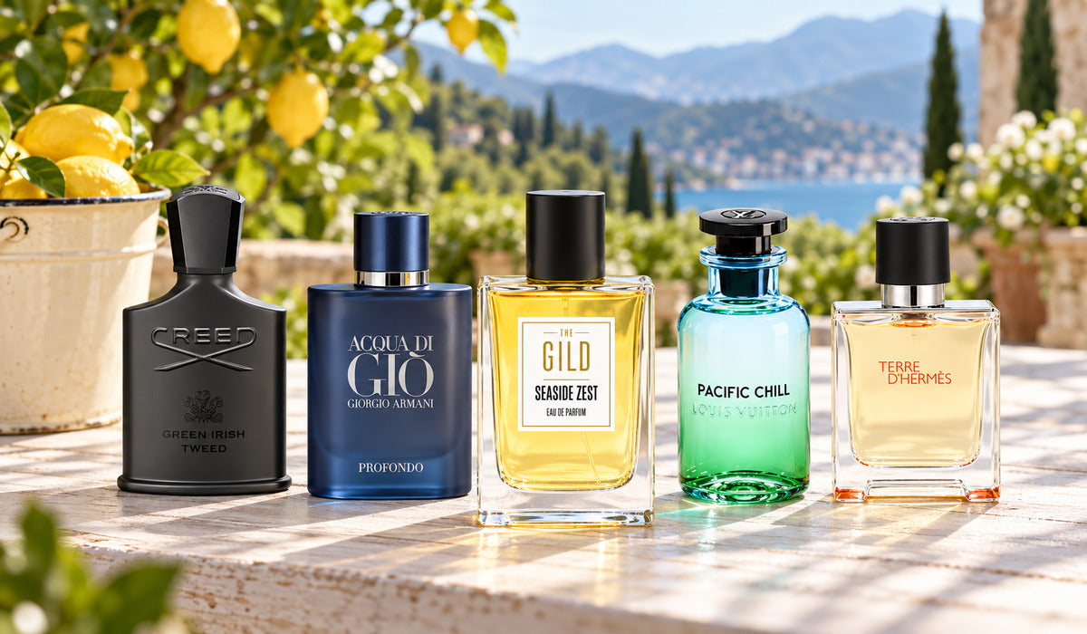 Seaside Zest, Pacific Chill, Acqua di Giò Profondo, Green Irish Tweed and Terre d'Hermès on a white wood table in an Italian garden, with a lemon bucket and blurred mountains.