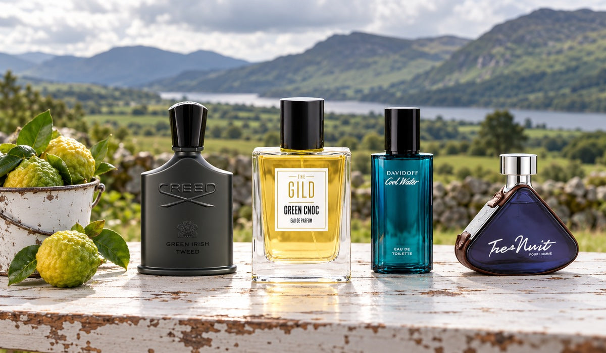 Green Cnoc, Creed Green Irish Tweed, Cool Water and Tres Nuit on a weathered white outdoor table with bergamot and blurred Irish mountains.